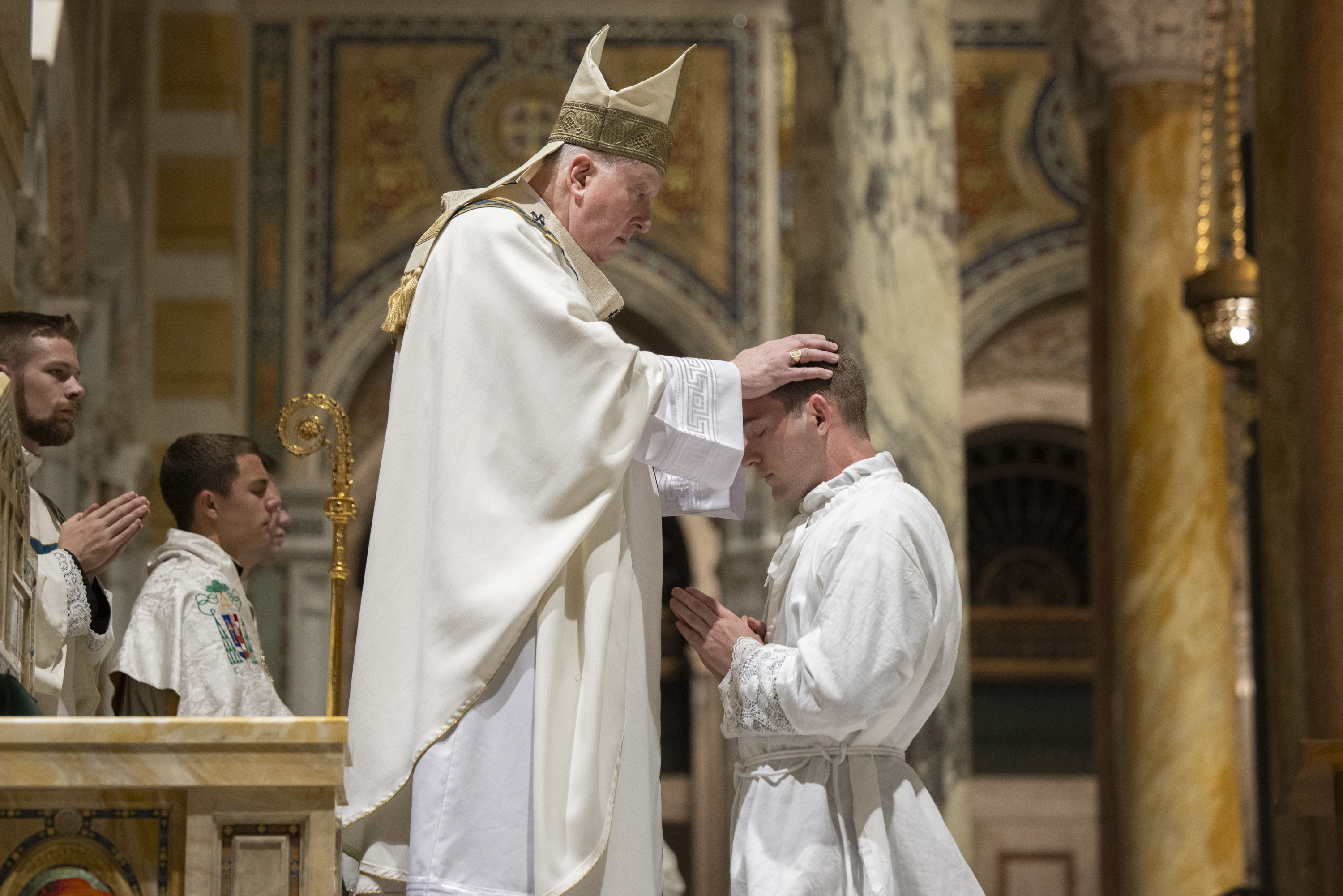 Archbishop Mitchell T. Rozanski placed his hands on the head of Curtis Prize at the rite of ordination.